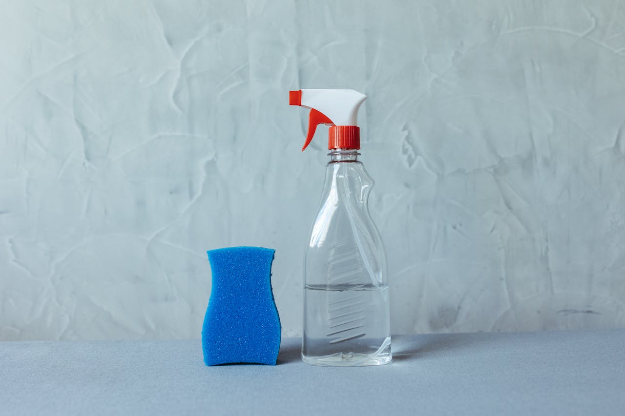 hero-img A spray bottle and blue sponge on a textured grey surface. Perfect for cleaning themes.